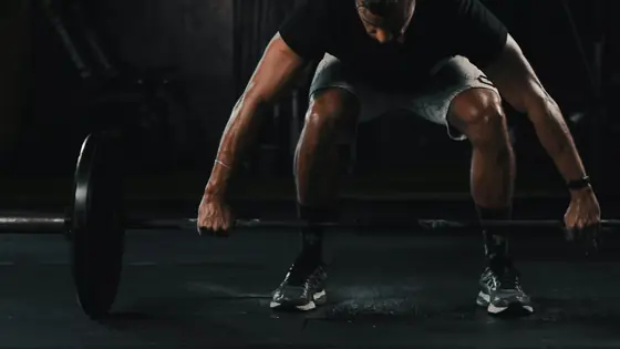 A man setting up a barbell deadlift with a flat back