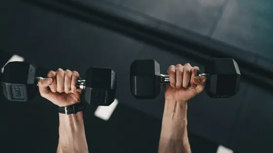 Two hands pressing dumbbells overhead